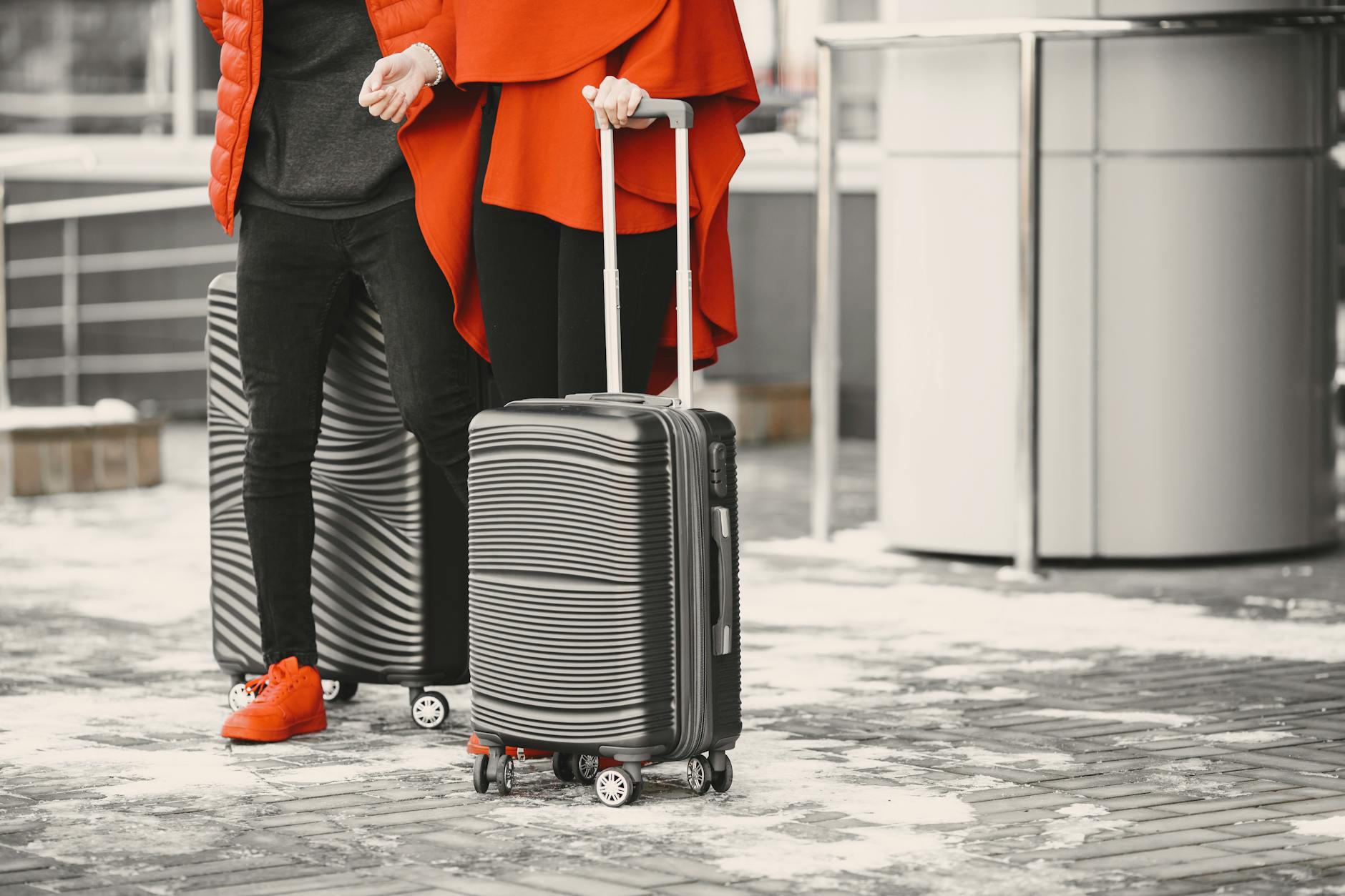 Travelers with luggage standing outdoors in snowy weather