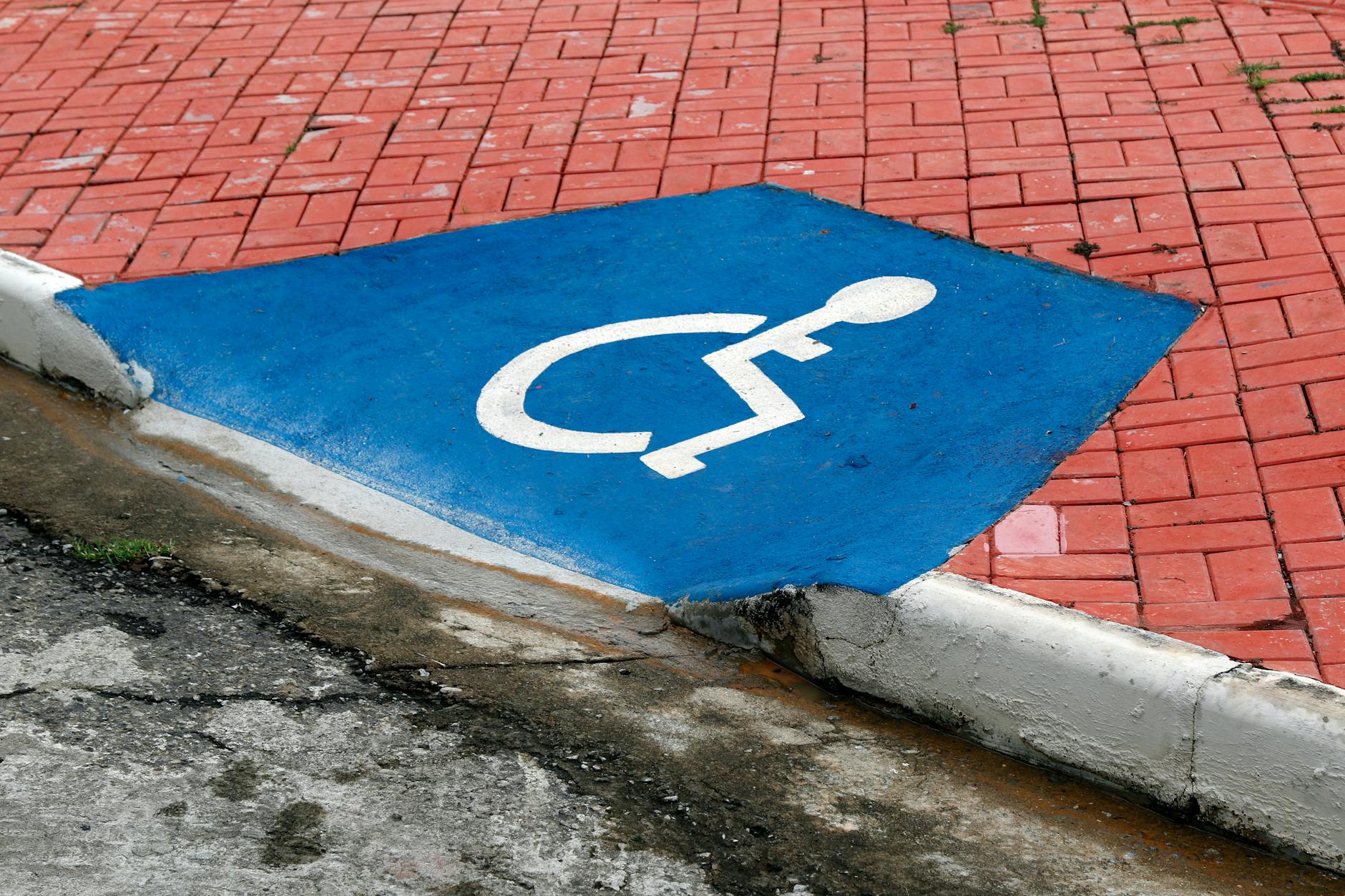 Blue accessibility parking symbol on brick pavement
