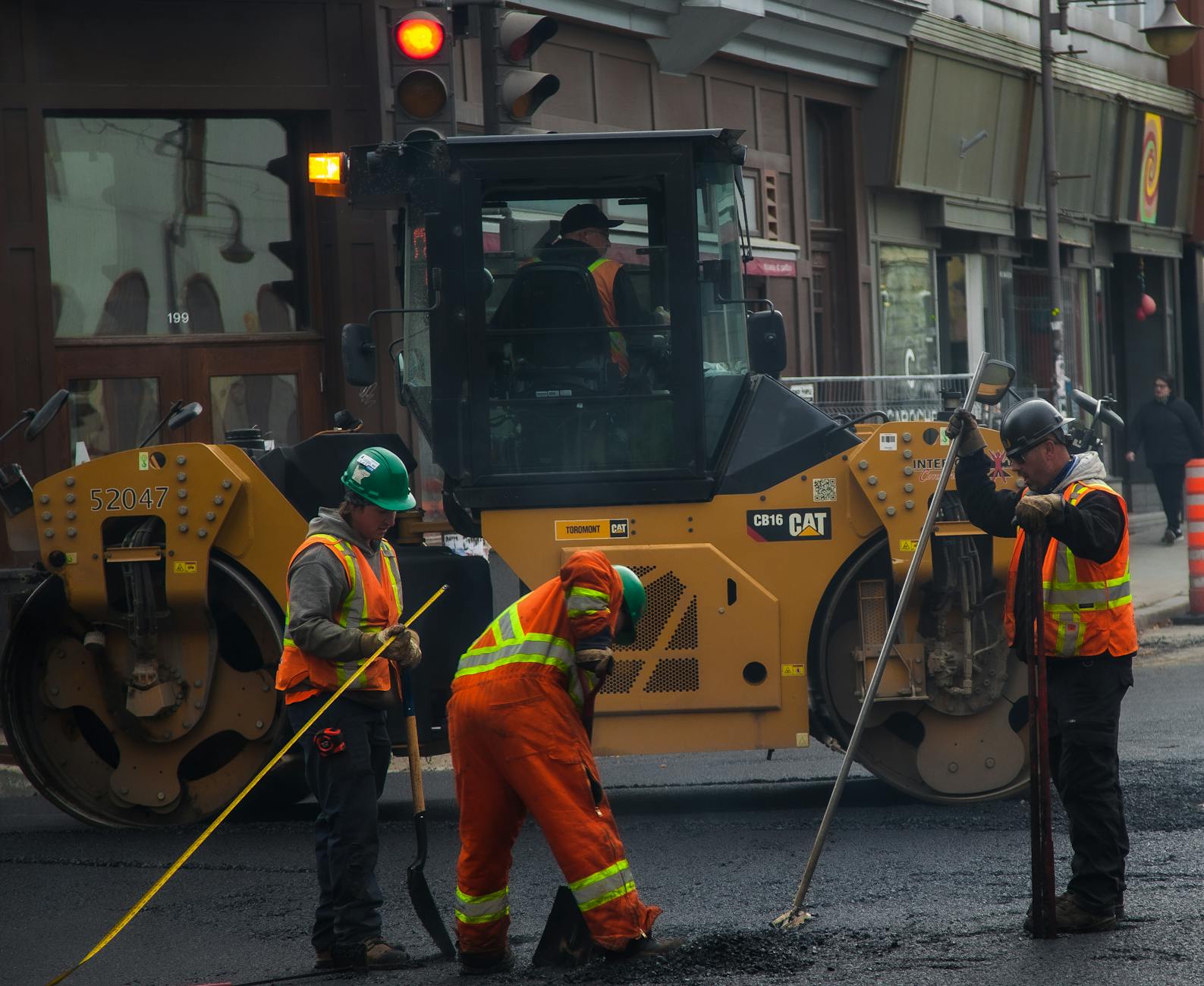 Workers and machinery paving a road in urban Quebec City