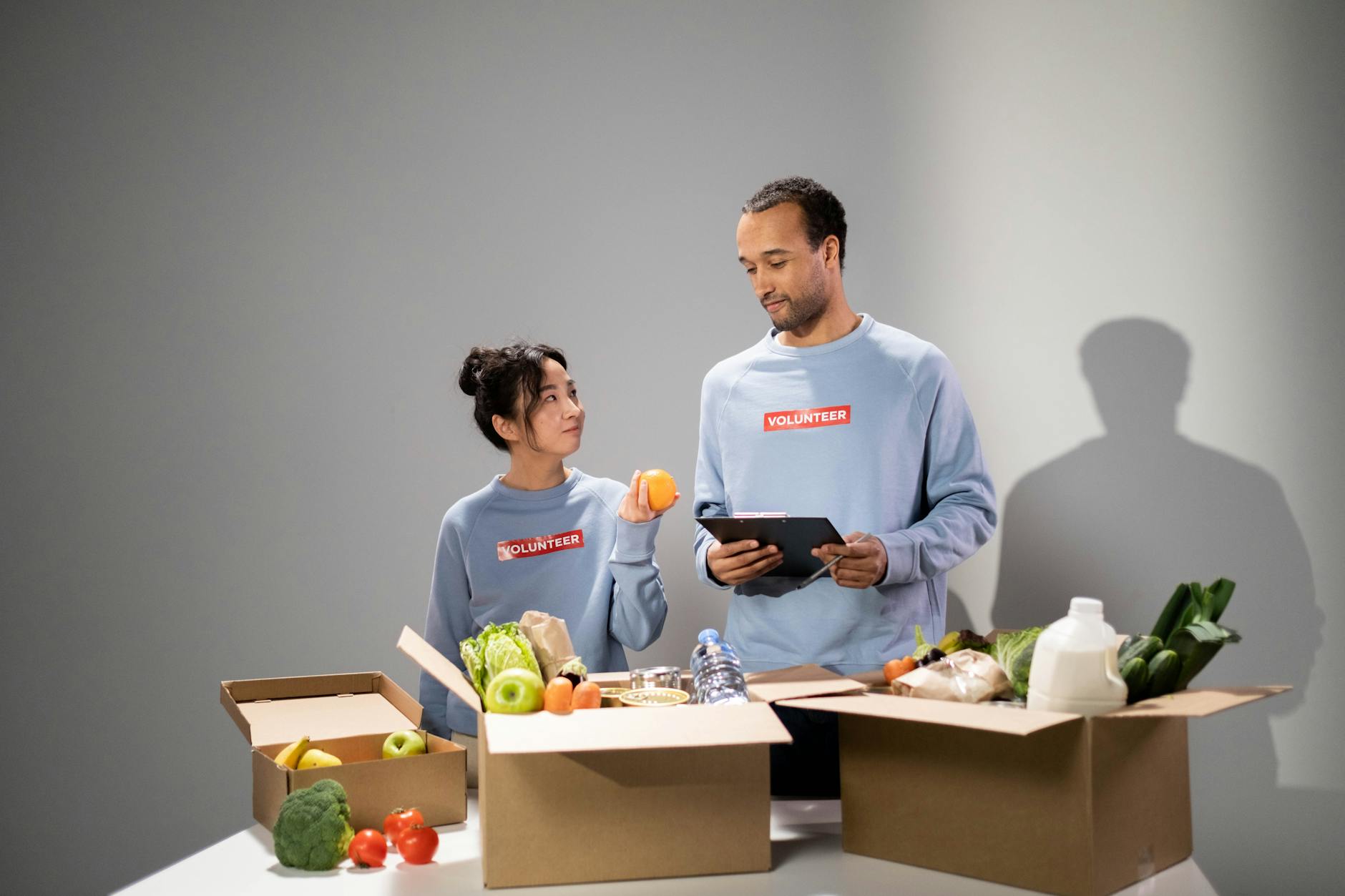 Volunteers organizing food items into boxes indoors