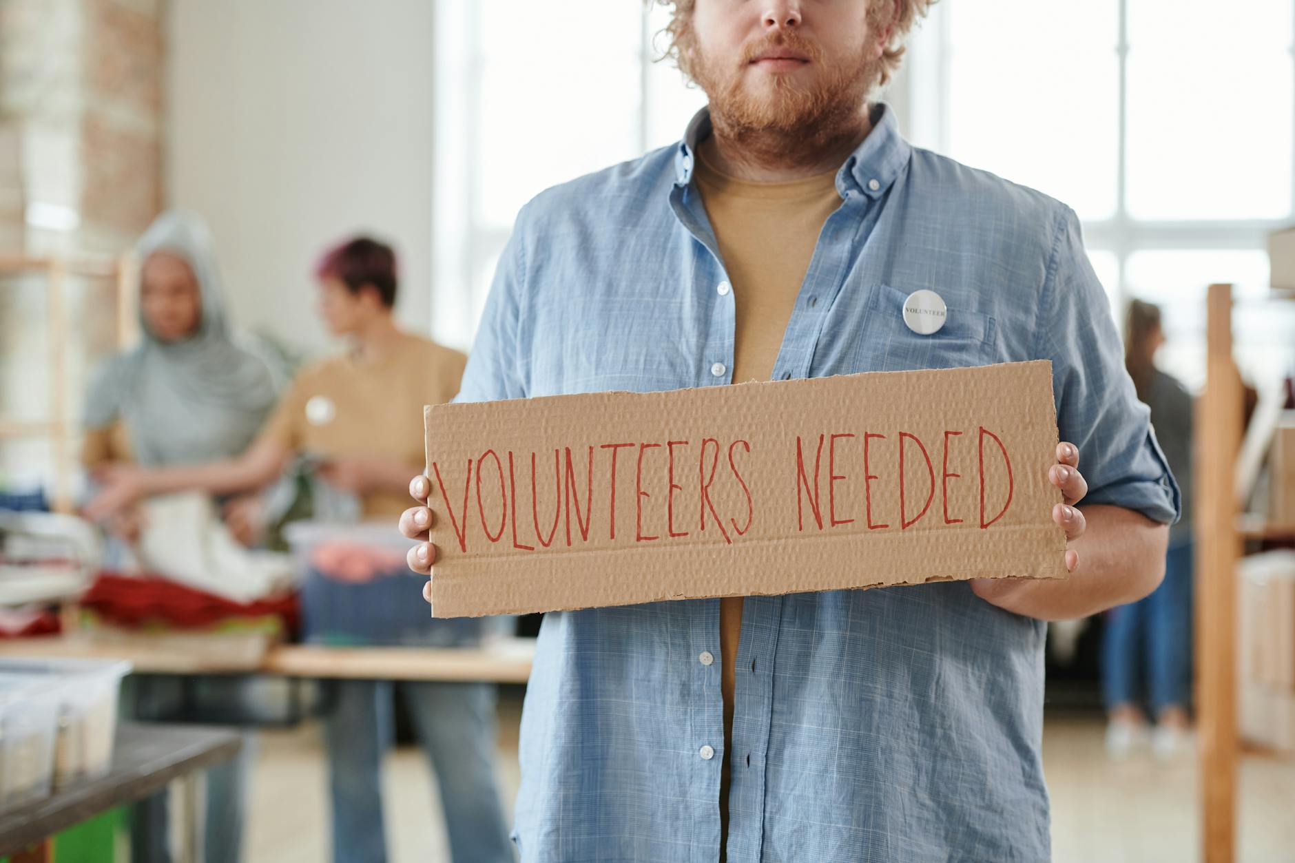 Person holding a volunteers needed sign at a charitable organization
