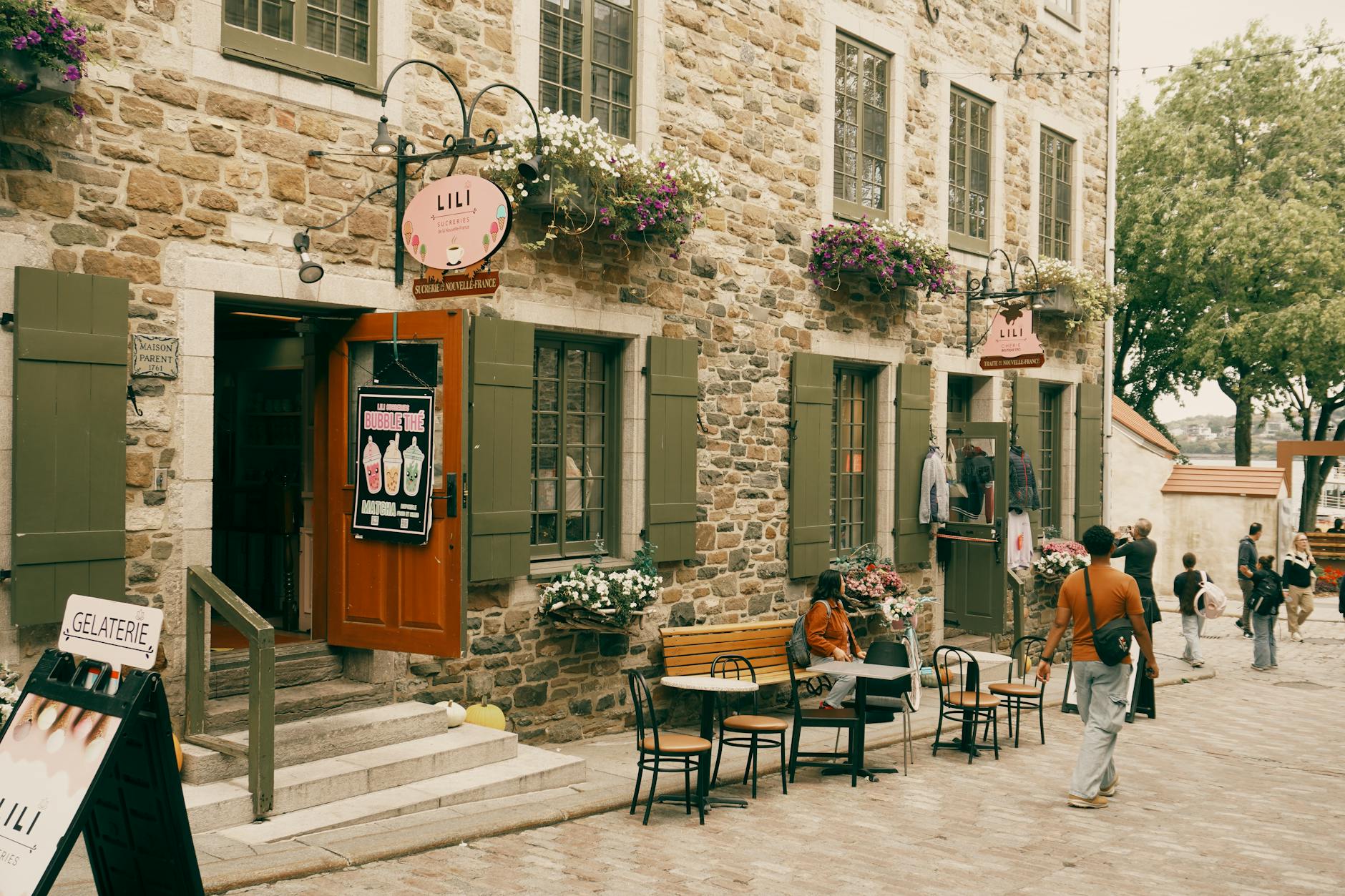 Stone building with flower pots and pedestrians in Old Quebec City