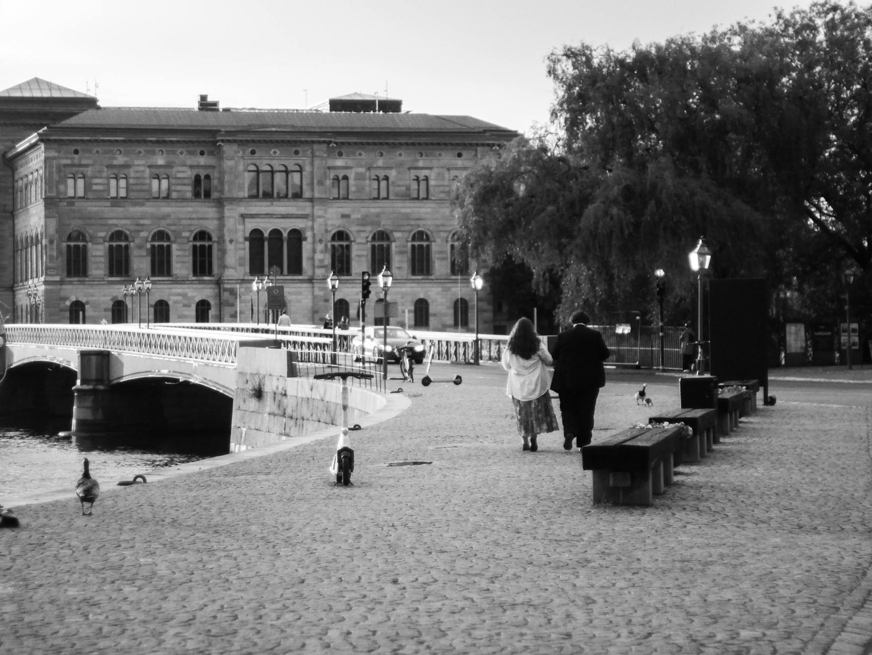Couple walking a Stockholm cobblestone path for creator location planning.