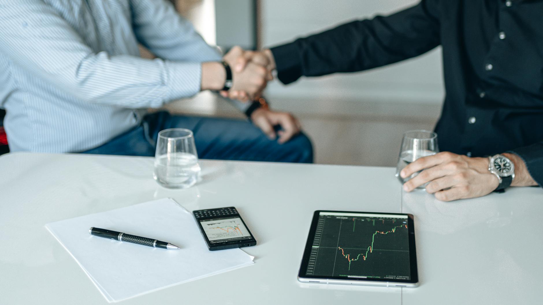 Financial meeting handshake for Stockholm deal-team negotiation planning.