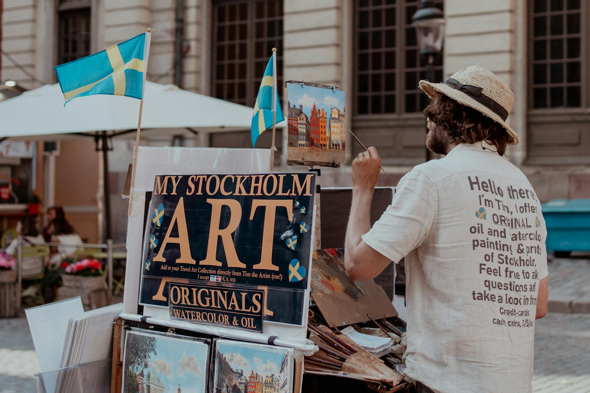 Street artist painting Stockholm scenes for tourist photo and souvenir planning.