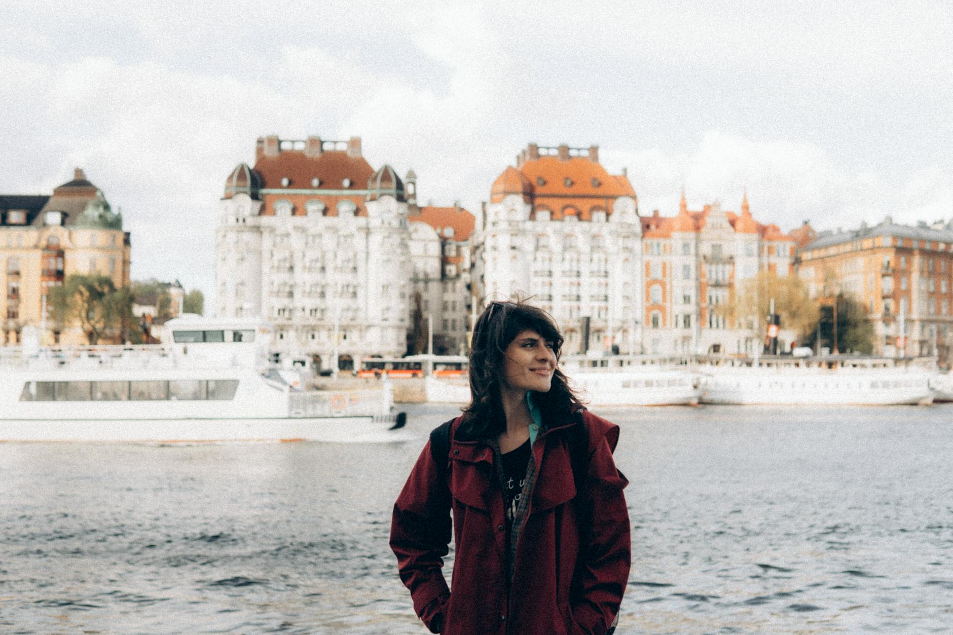 Woman smiling by the Stockholm waterfront for woman traveler planning.