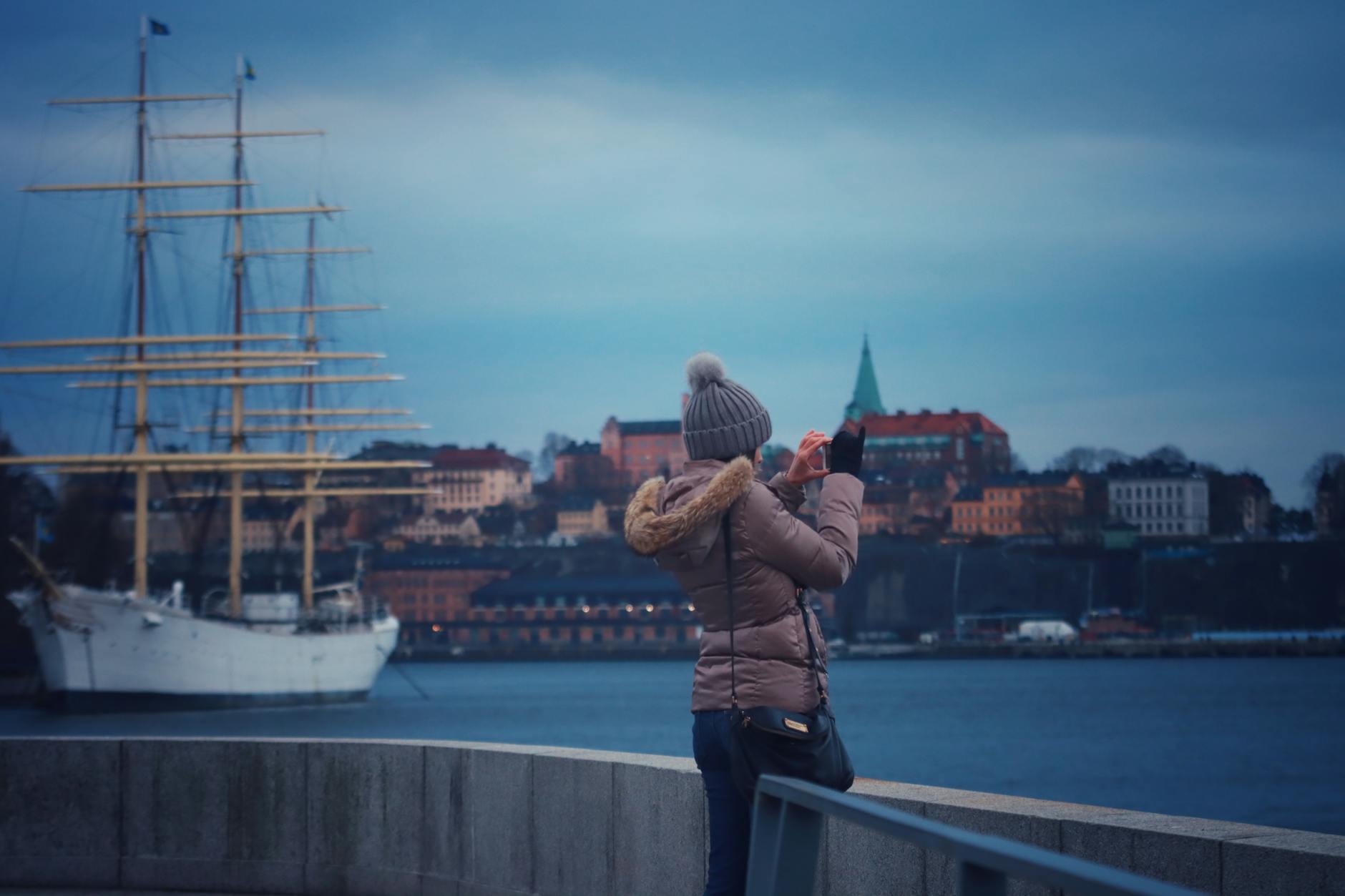 Woman photographing a ship in Stockholm harbor for personal pacing planning.