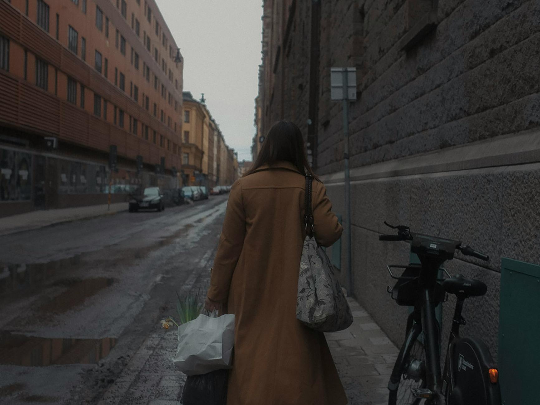 Woman walking on a wet Stockholm street for hotel-return planning.