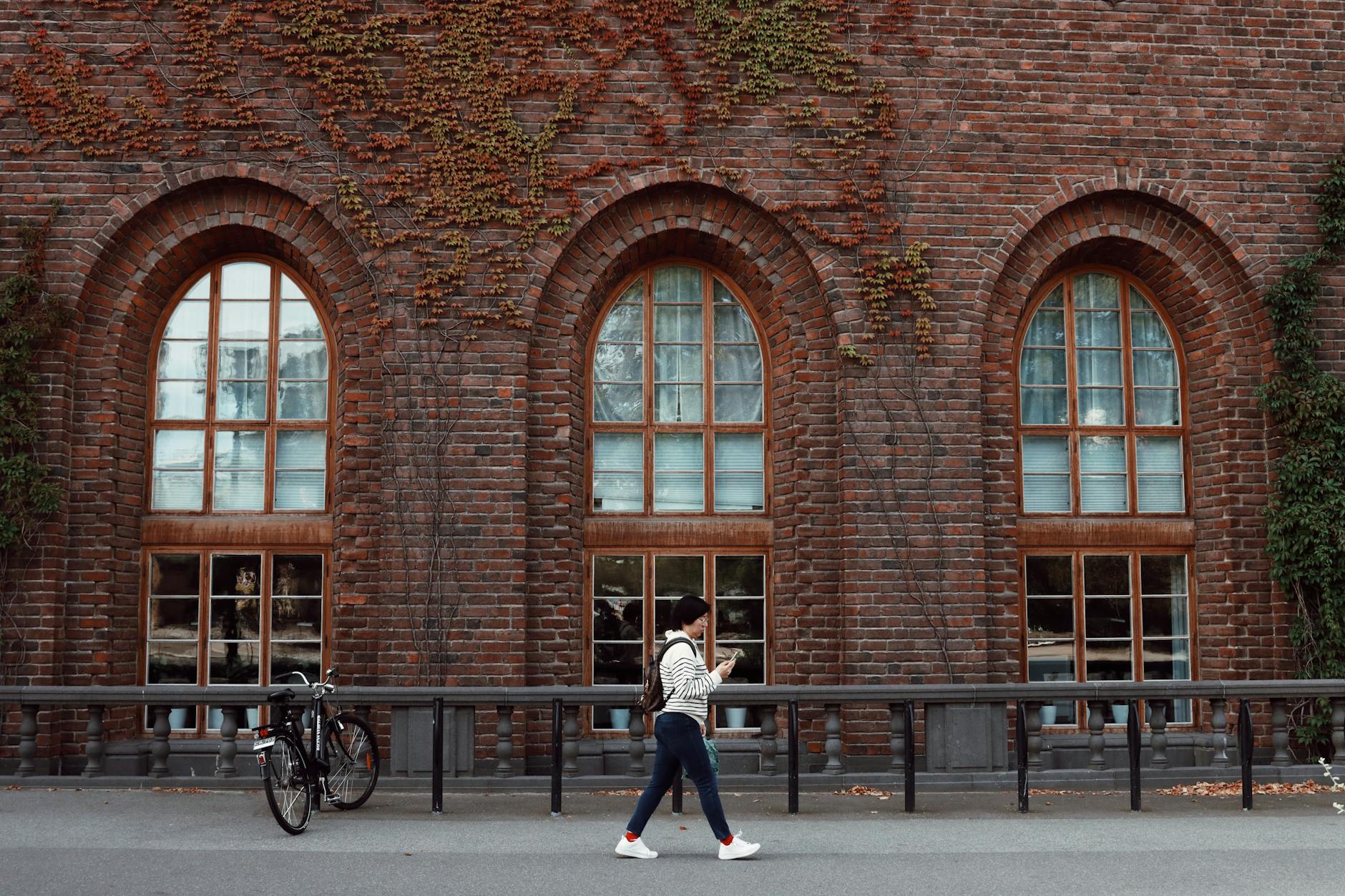 Woman walking past a brick building in Stockholm for neighborhood planning.