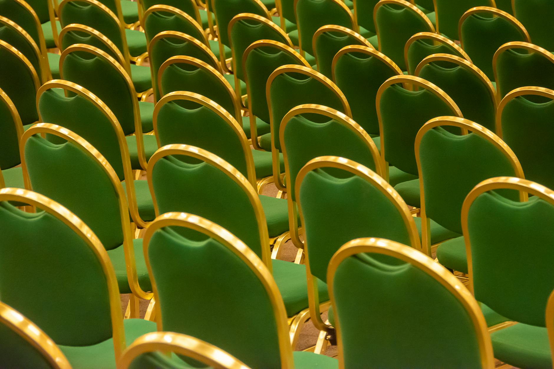 Rows of green chairs in an empty auditorium