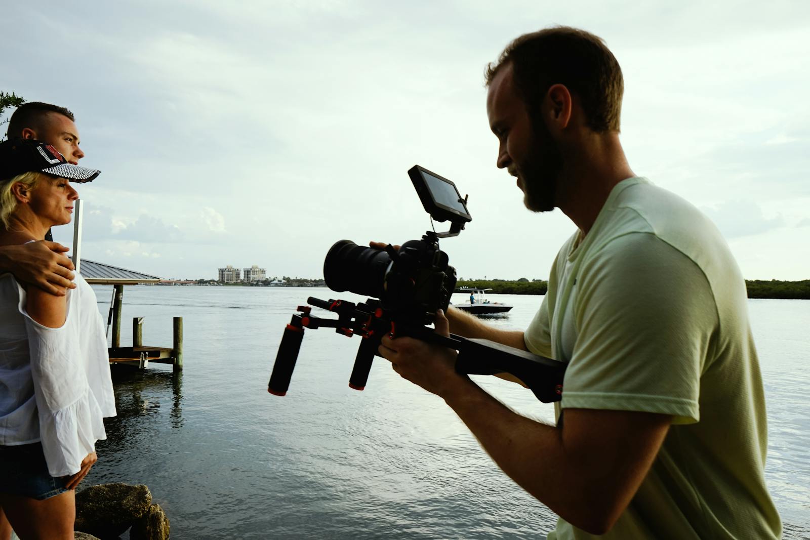 Cinematographer records a couple by the waterfront with a professional camera setup.
