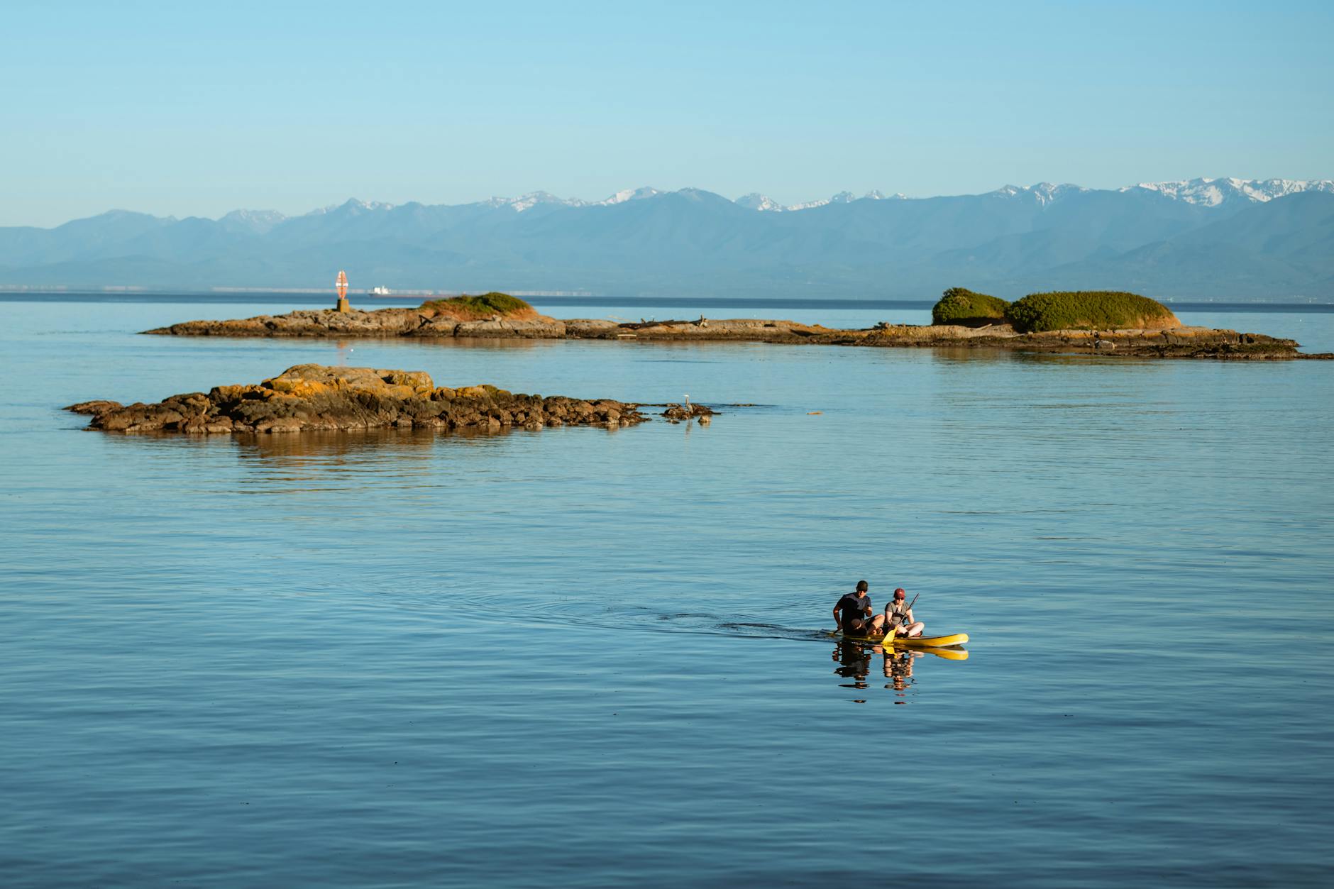 Two people kayaking near rocky islands in British Columbia