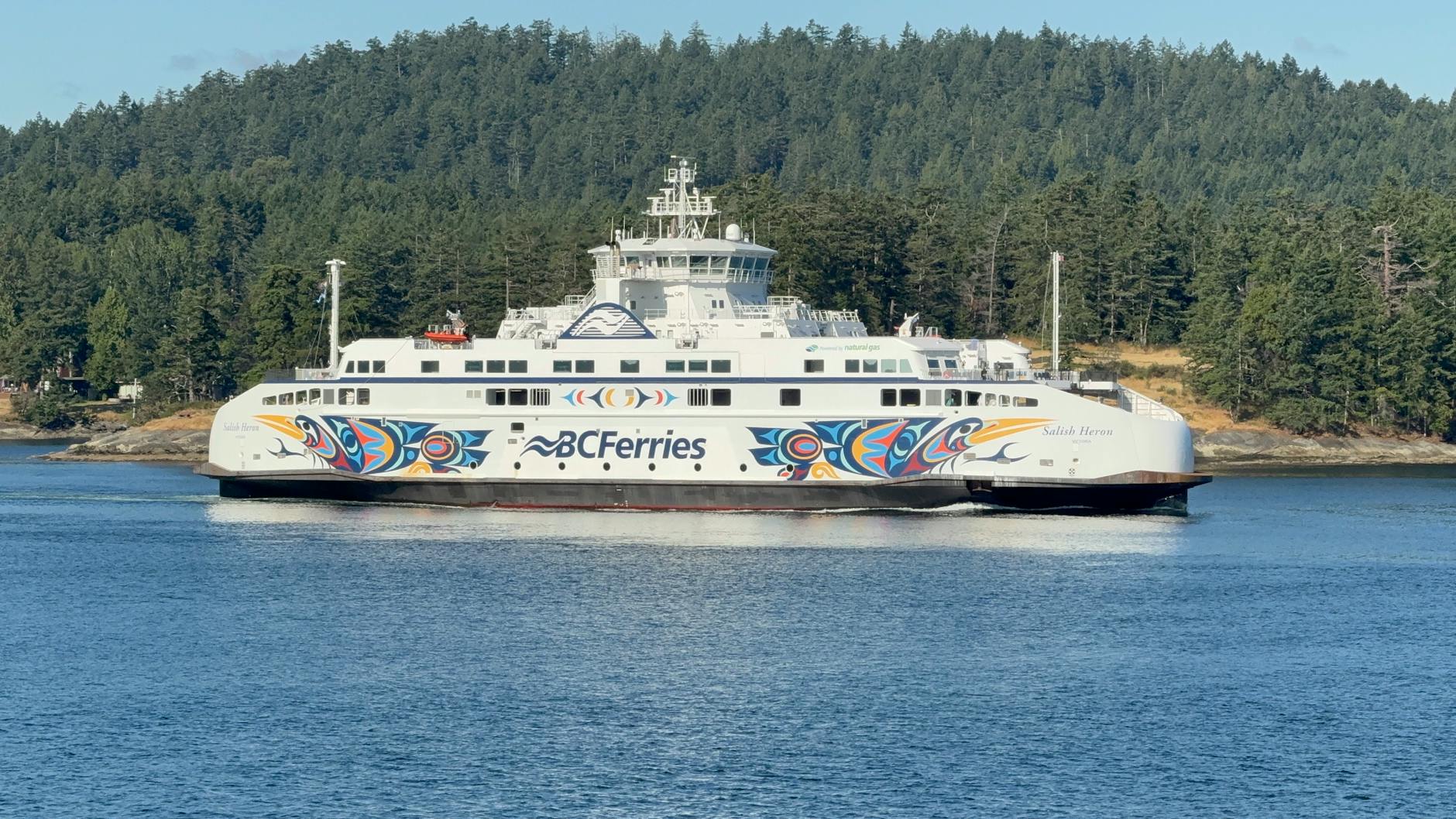 BC Ferries ship sailing through calm water and forested coastline