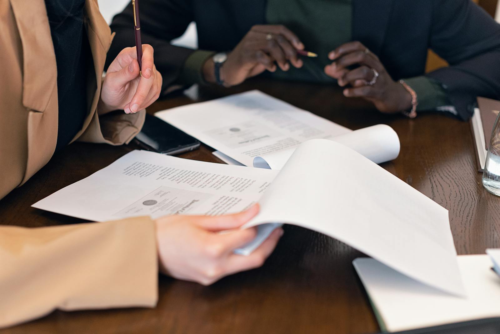 Close-up of professionals reviewing documents during a business meeting in an office setting.