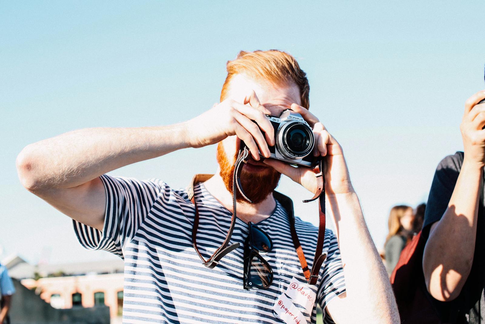 Photographer concentrating on taking a picture with a vintage camera at a street event.
