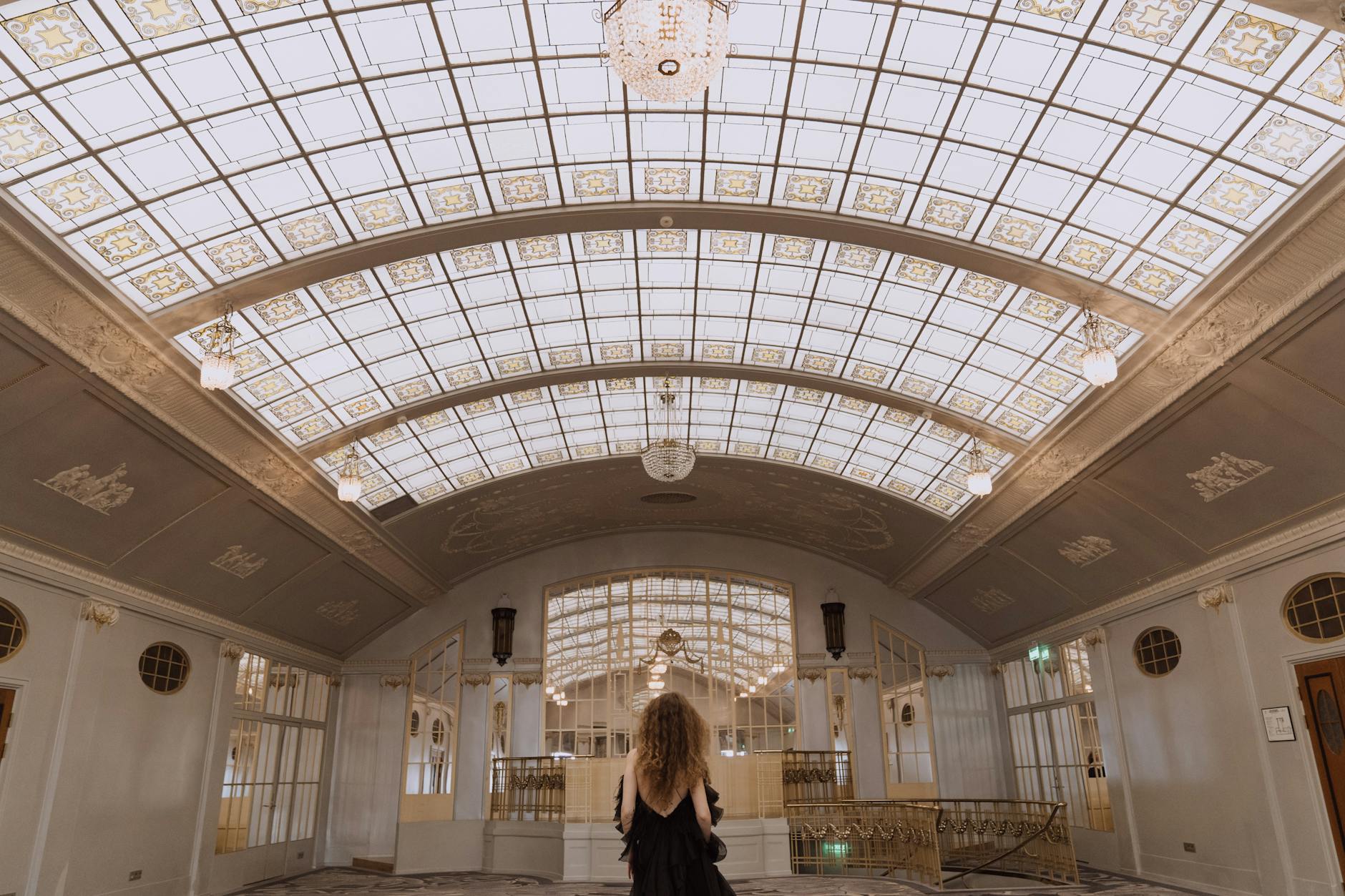 Woman standing beneath a luxurious glass ceiling in a hotel lobby