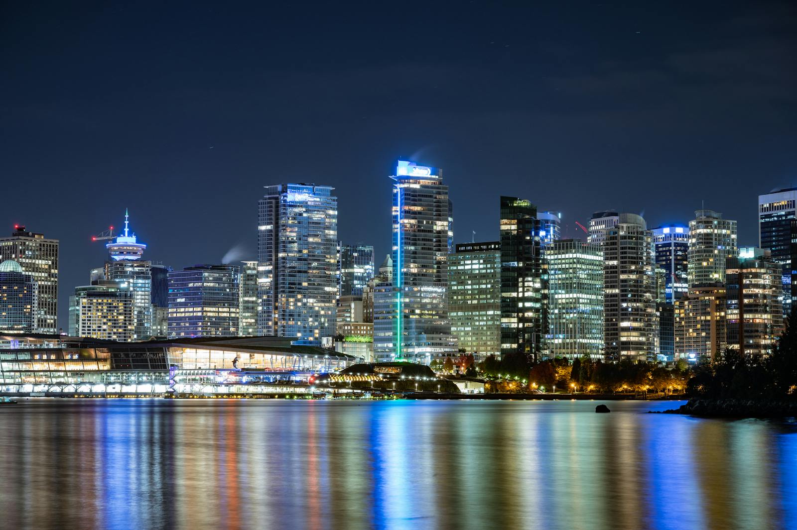 Night view of Vancouver's illuminated skyline reflecting on the water.