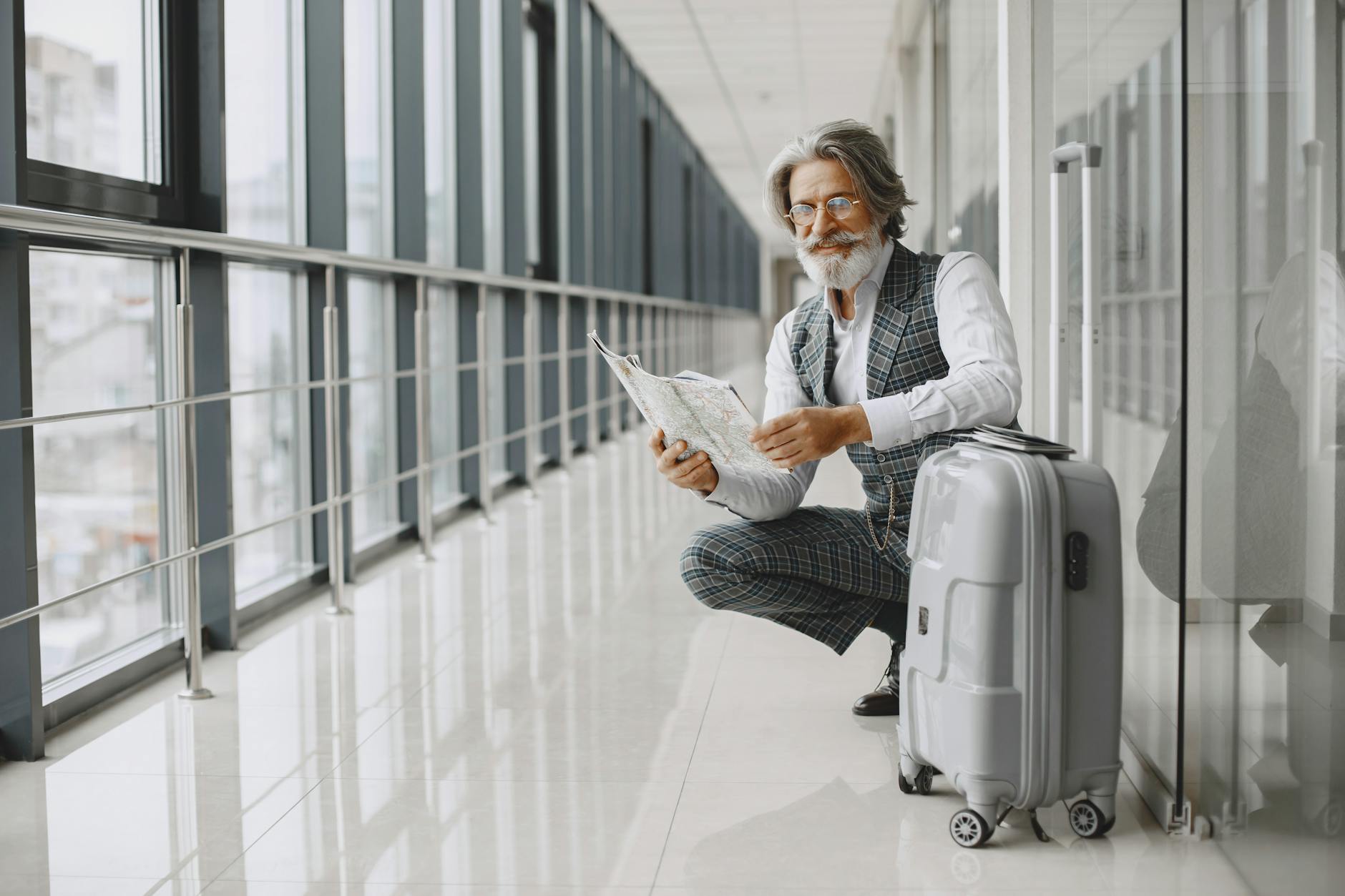 Senior man with luggage and map in an airport hallway
