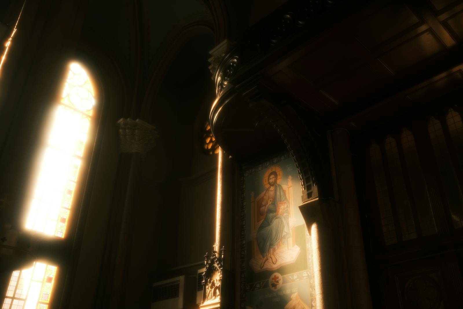 Sunlight streaming through stained glass in a church with religious art and iconography.