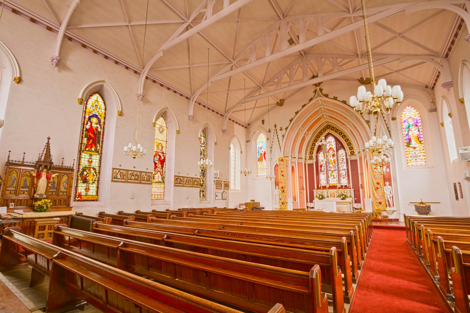 Interior view of a historic church with ornate stained glass and wooden pews.