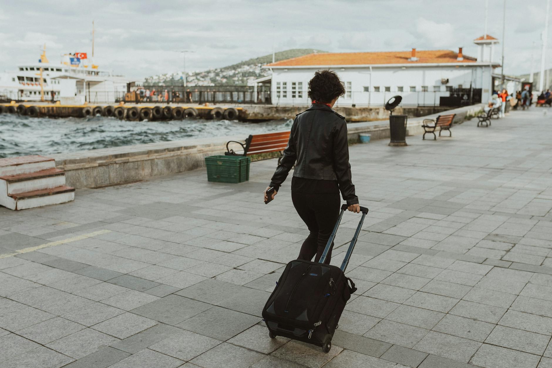Woman walking on a seaside promenade with a suitcase
