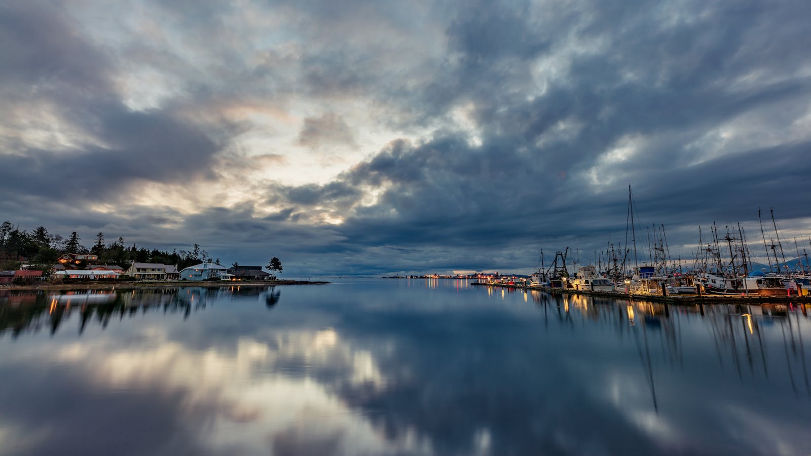 A tranquil view of Comox Fisherman's Wharf at dusk, with calm waters and cloudy skies.