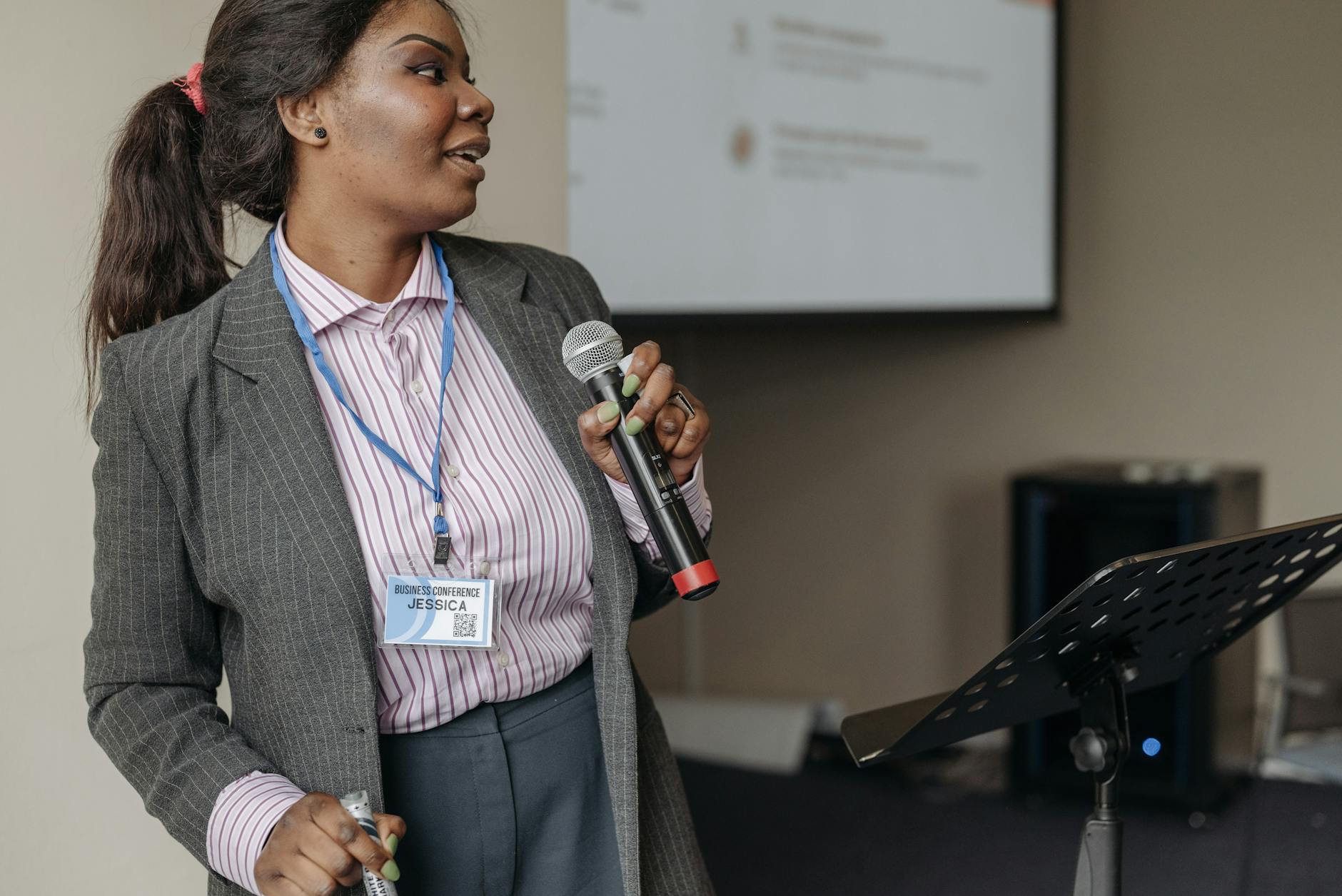 Woman in professional attire presenting at a business seminar with microphone.
