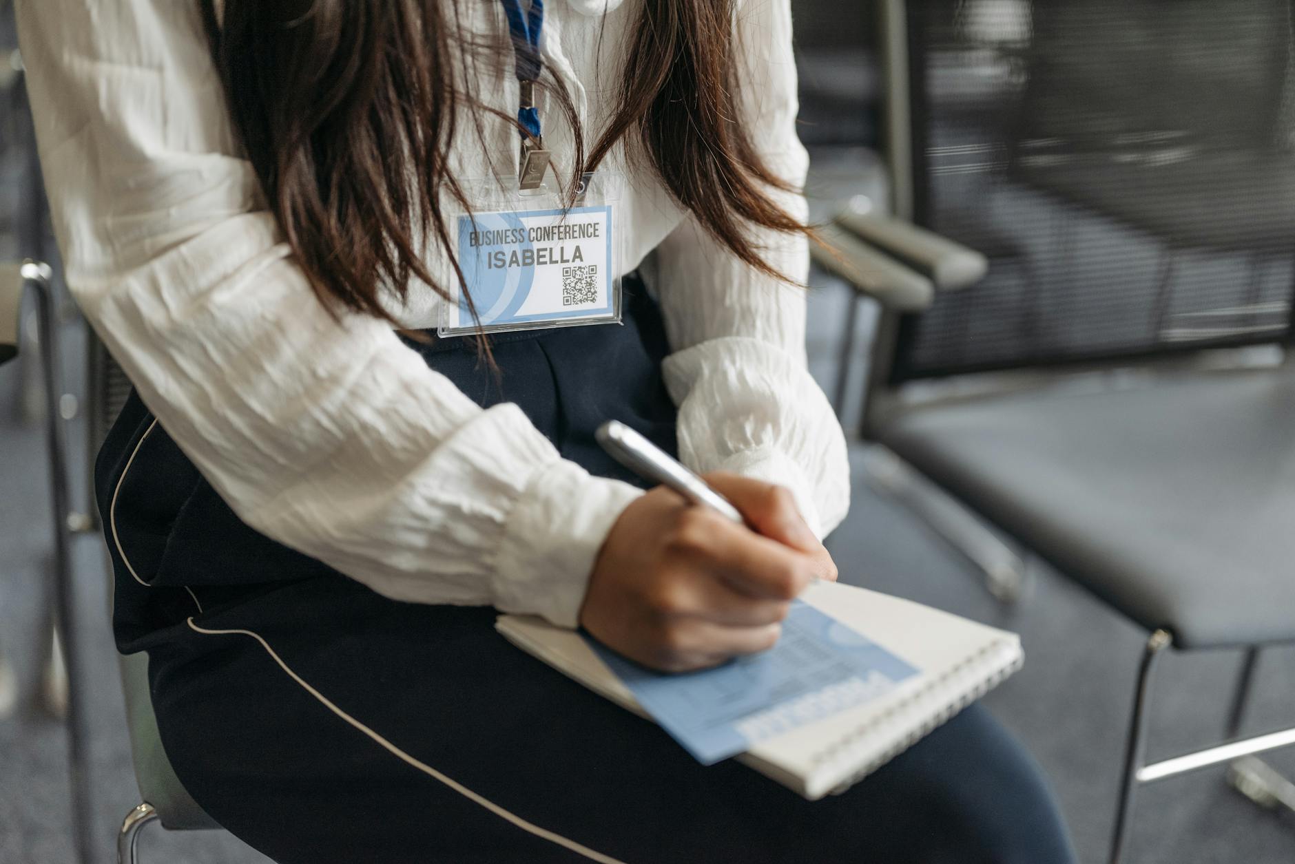 Businesswoman in a white blouse takes notes during a conference.