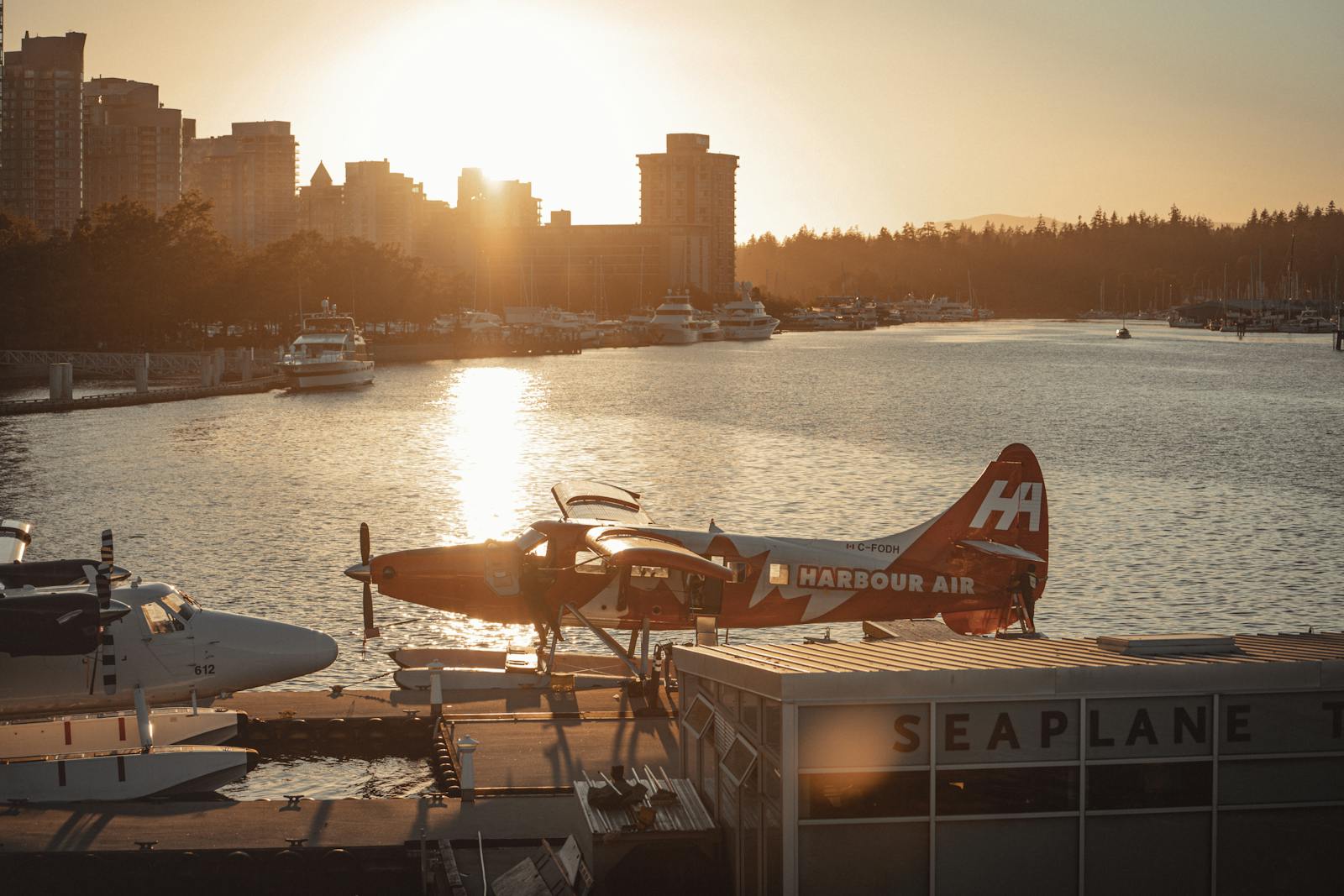 Sunset view of seaplanes at Vancouver Harbour with city skyline in the background.