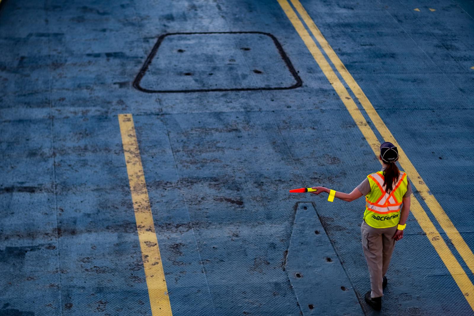 BC Ferries worker directing traffic on the ferry deck in a high-visibility jacket.