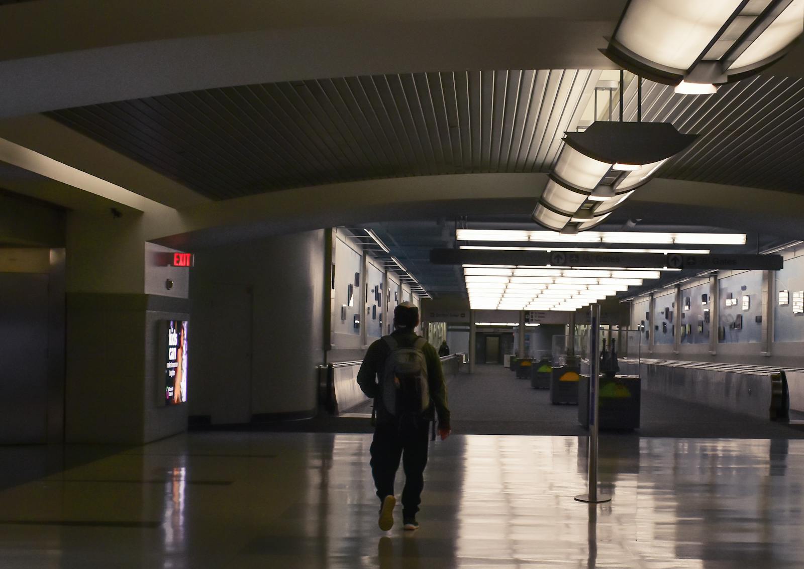 Silhouette of a traveler walking through a modern airport terminal at night.