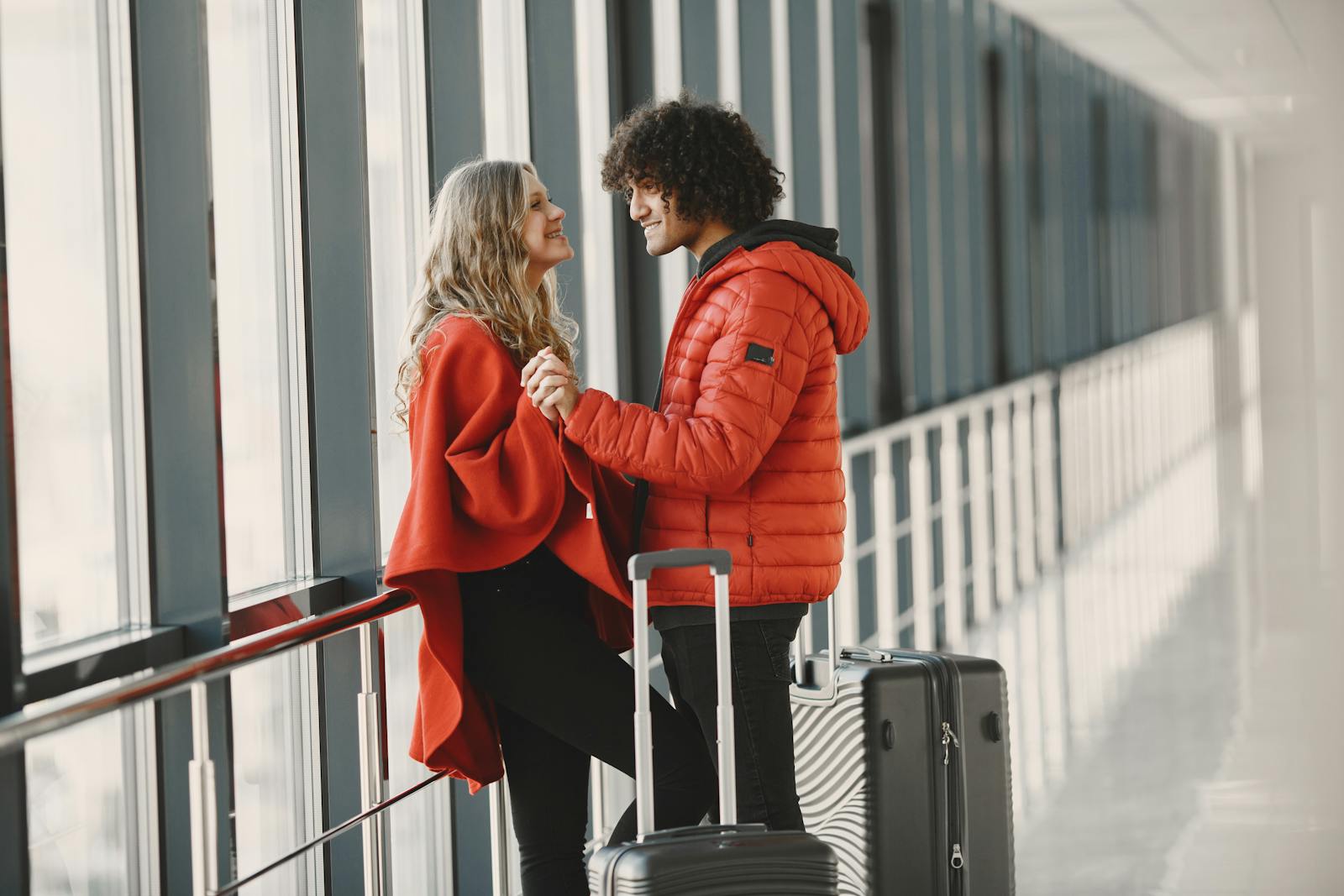 Cheerful couple holding hands with luggage in an airport terminal.