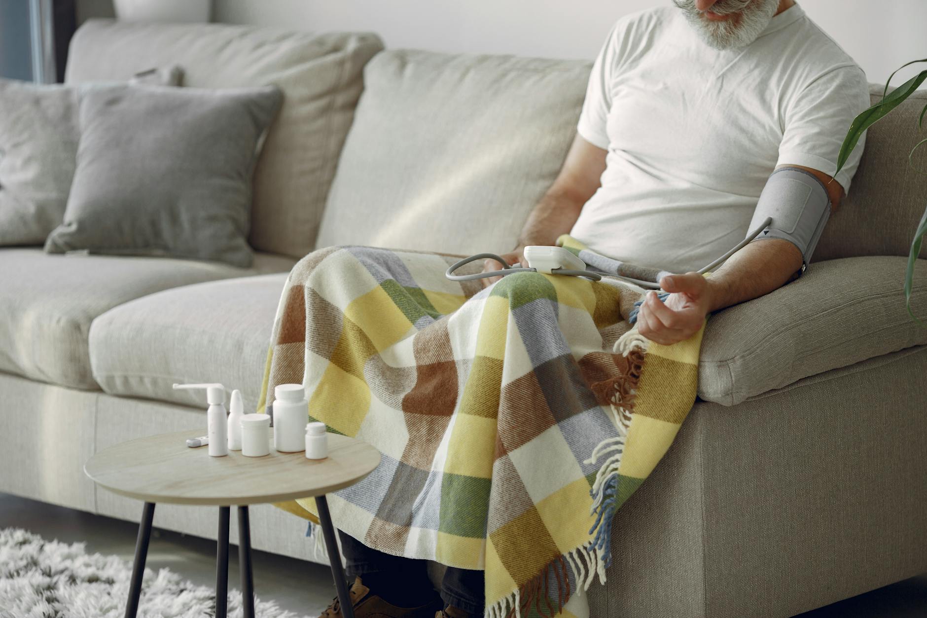 Older man checking blood pressure at home near medication