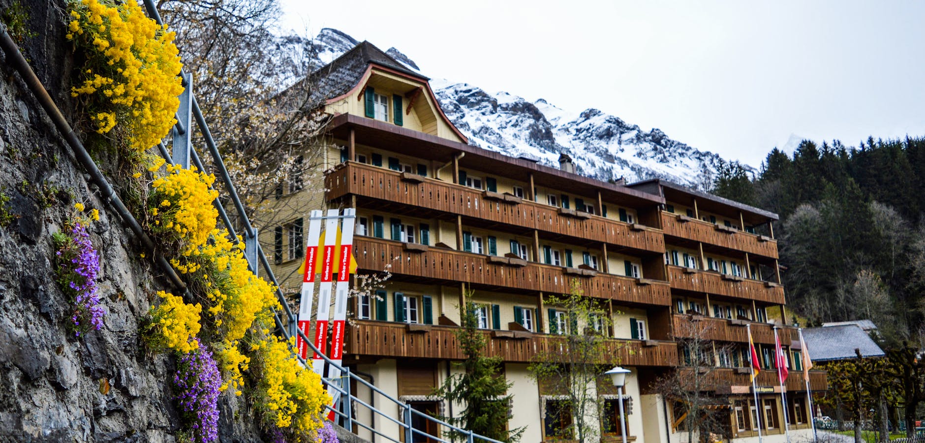 Alpine building and flowers near snowy mountains for Zermatt family weather planning.