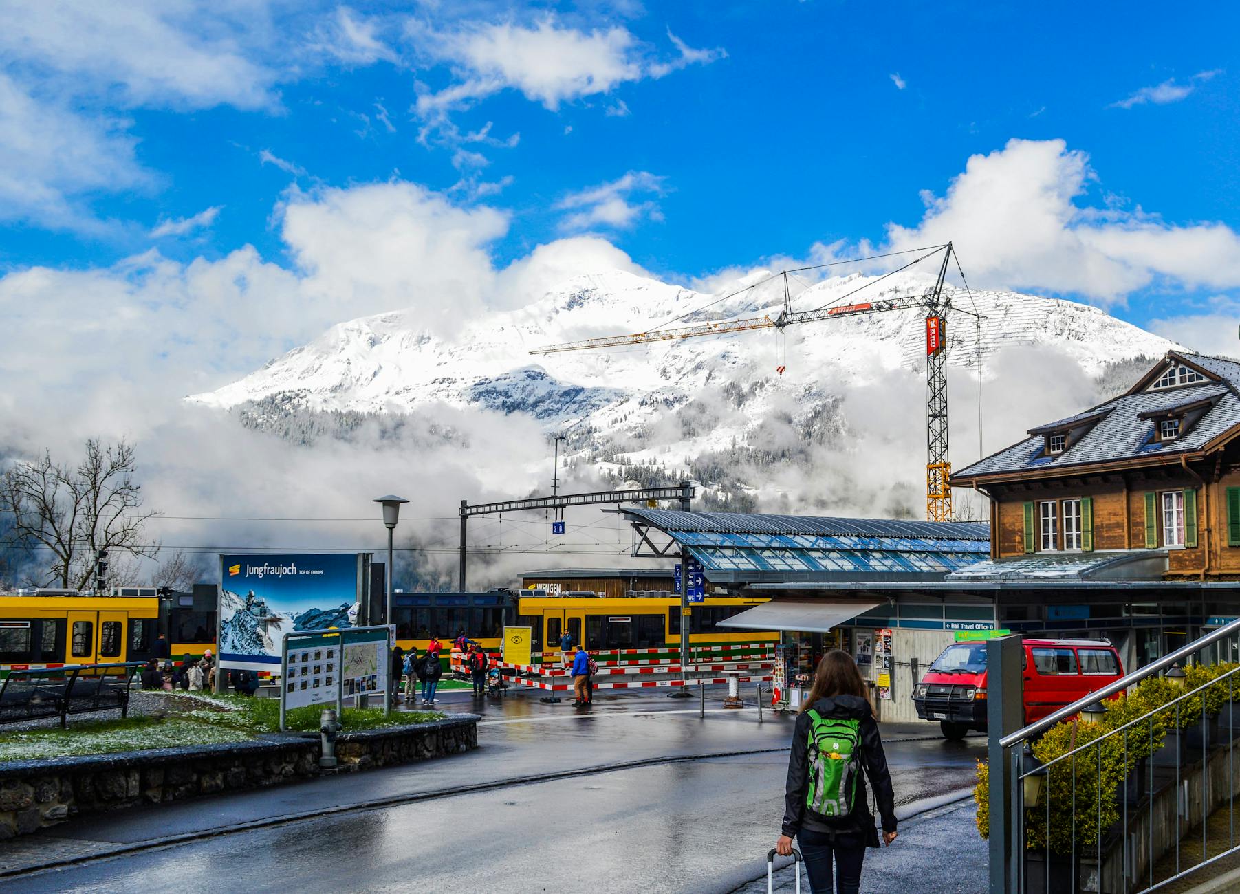 Traveler with suitcase near a Swiss train station for Zermatt arrival planning.