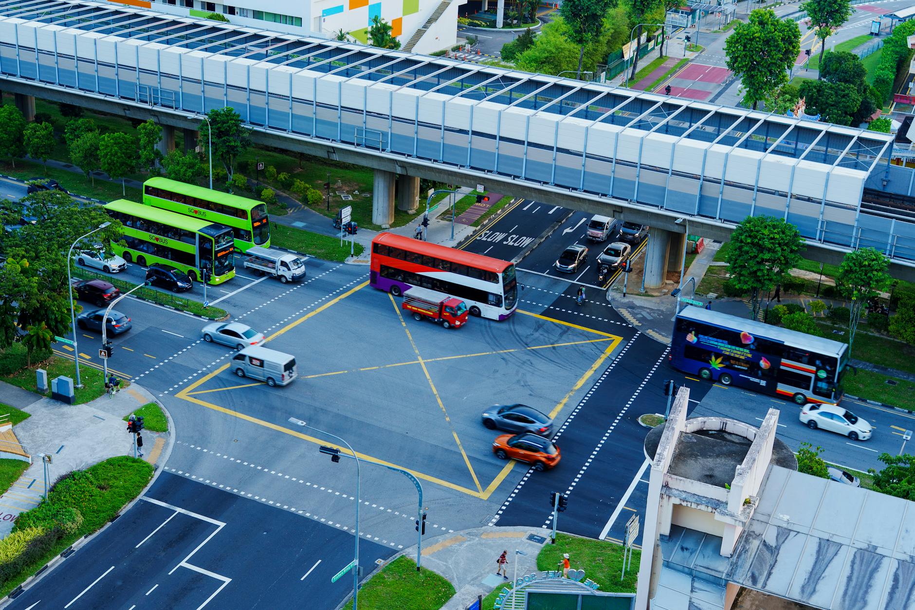 Buses and traffic moving through a Singapore city intersection.
