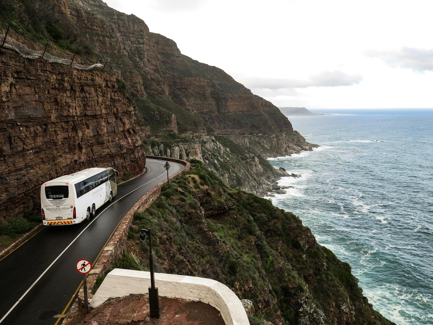 Coach moving along a cliffside coastal road in South Africa.