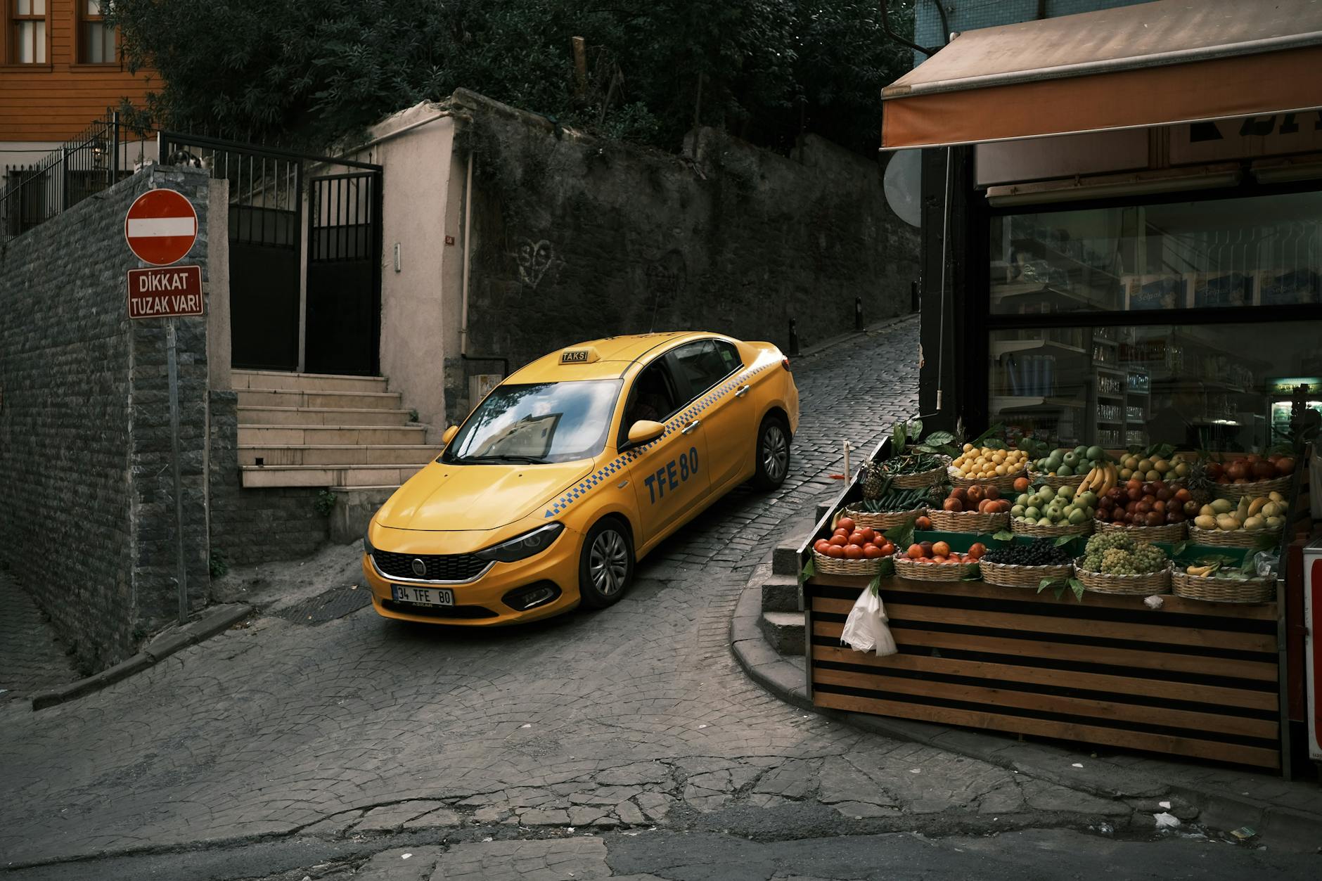 Yellow taxi climbing a narrow Istanbul street.