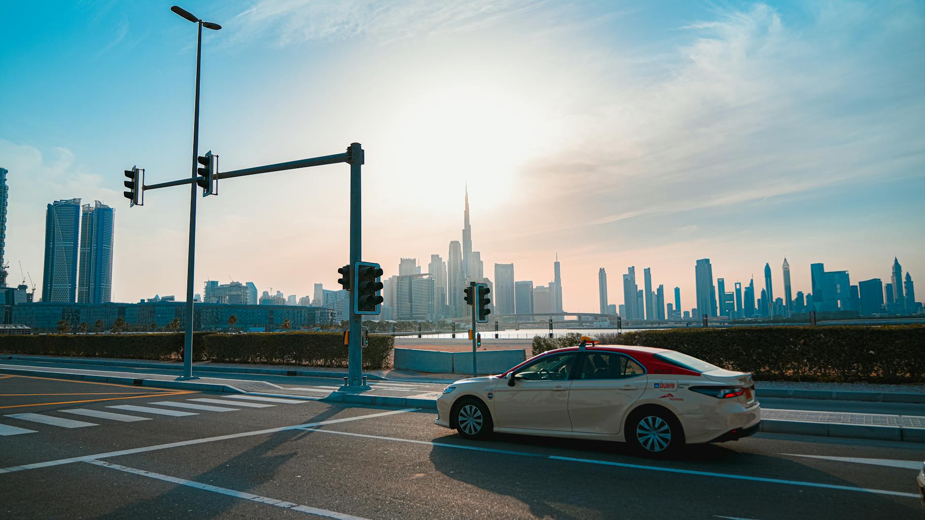 Taxi and road traffic moving through Dubai at dusk.